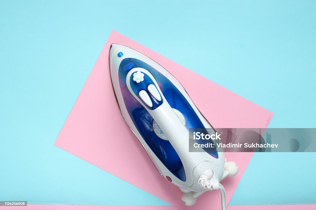 Iron for ironing on a colored pastel background, top view. Minimalism Iron - Appliance Stock Photo