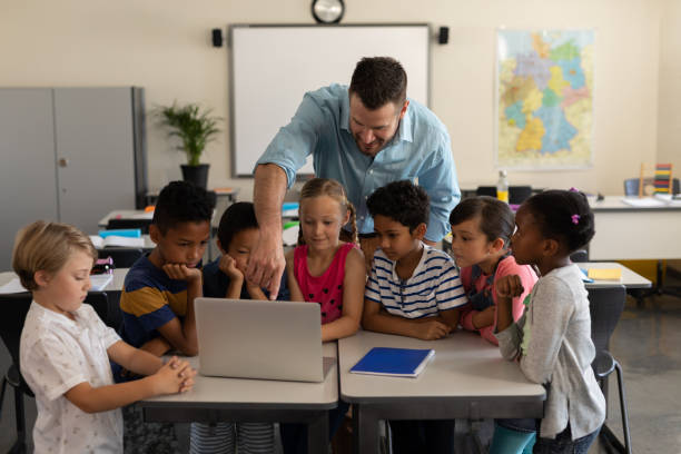 istock Male teacher teaching kids on laptop in classroom 1126208264