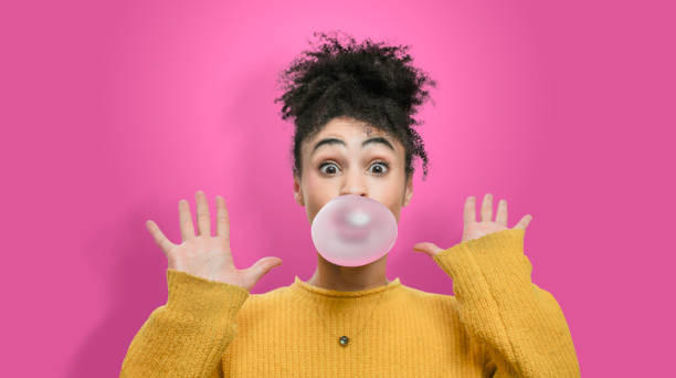 istock Woman blowing bubble on pink background 1126214074