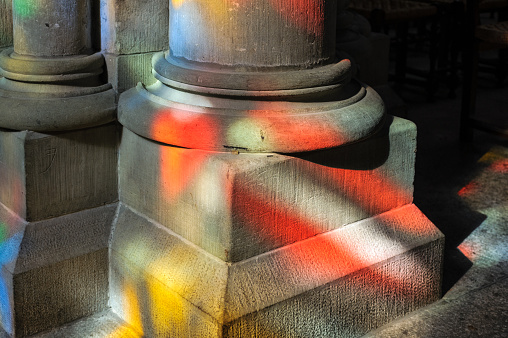 Sunlight through stained glass on pillars of a church