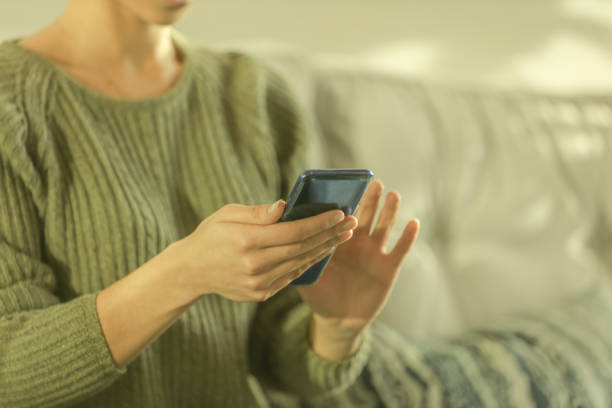 istock Young woman looking at phone in sun drenched lobby 1126216775