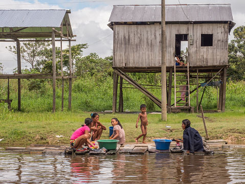 Belen, Peru- March 27, 2018: Family doing laundry in the river.  Floating houses in the floodplain of the Itaya River, poorest part of Iquitos - Belén. Venice of Latin America.Region Loreto, Province Maynas.