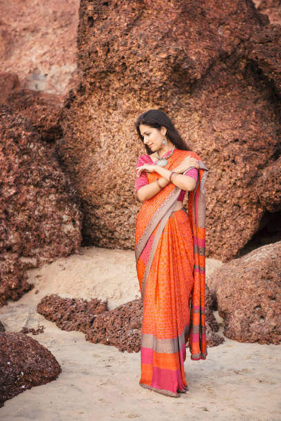 istock Indian woman in beautiful saree posing on beach at sunset 1126218946