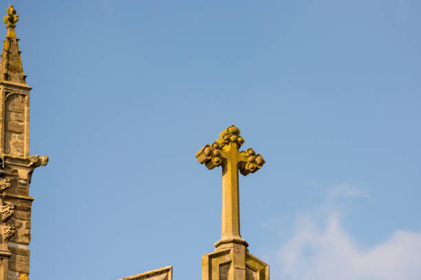 stone cross on church roof with blue skies in background