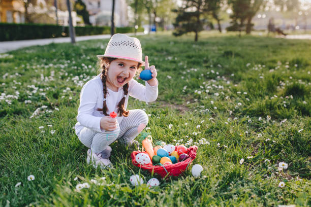 porträt eines vier jahre alten mädchens hält ein ei fand sie während eine ostereiersuche - child discovery outdoors playing stock-fotos und bilder