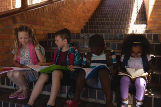 istock Schoolkids reading book while sitting on stairs of elementary school 1126232968