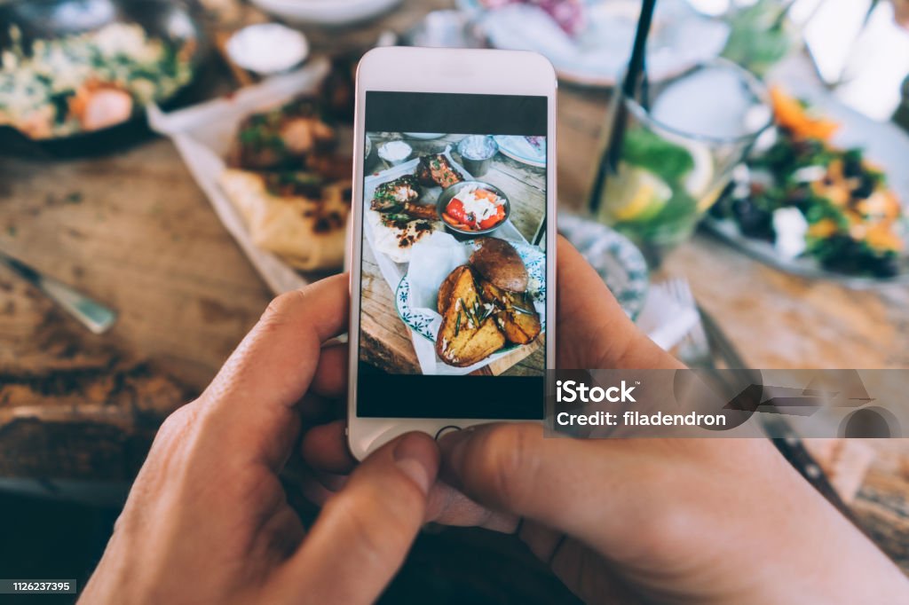 Sharing food Taking Photo with Smartphone of tasty meal  for social media before eating it Photograph Stock Photo