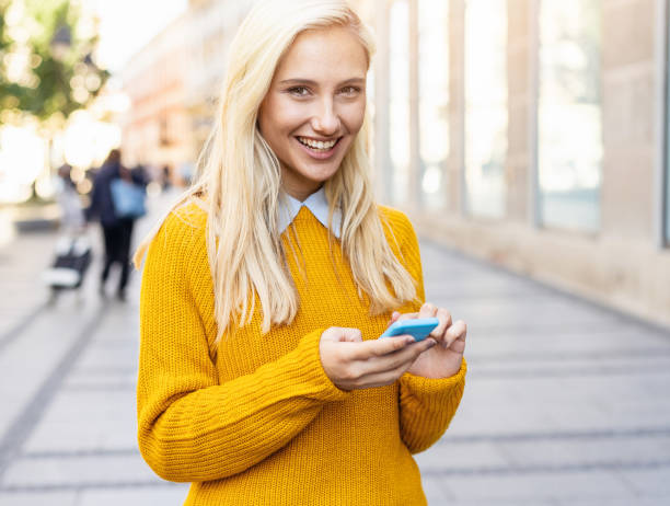 istock Young blond woman texting on the street 1126237398
