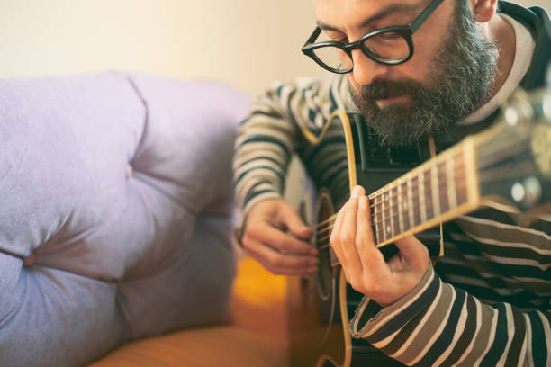 istock A man playing guitar at home 1126248598