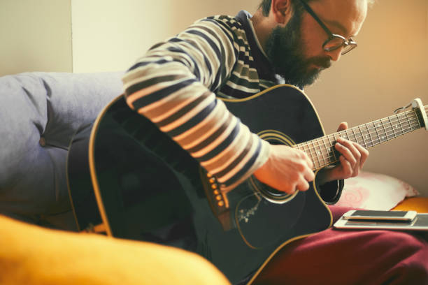 istock A man playing guitar at home 1126248660