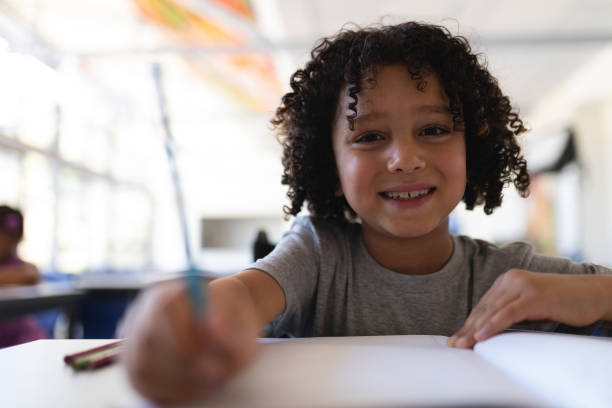 istock Happy schoolboy looking at camera at desk in classroom 1126254922
