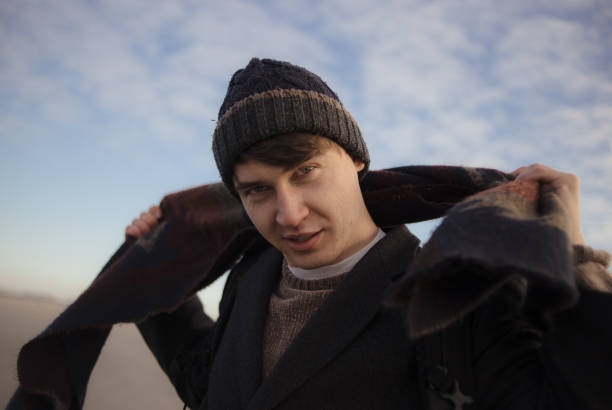 Young beautiful man tying scarf