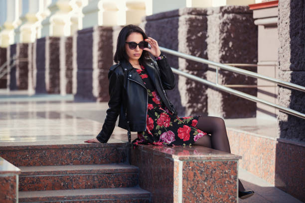 mujer joven feliz en chaqueta de cuero y gafas de sol - floral dress fotografías e imágenes de stock