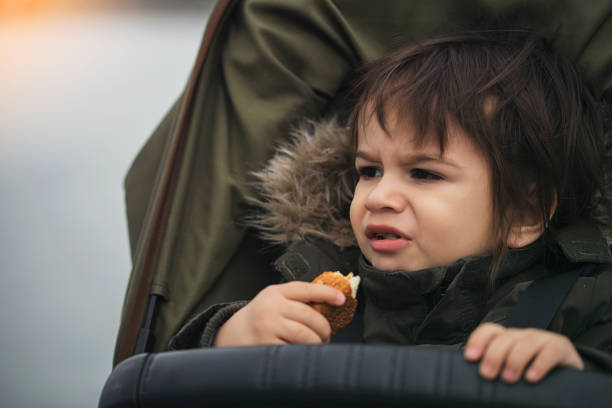 istock A small child sitting in a stroller and eating bagel 1126257214
