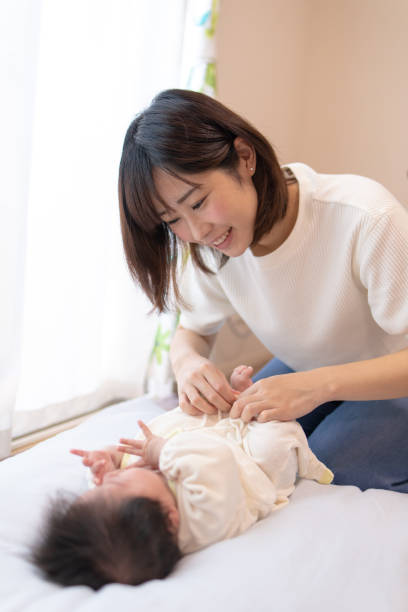 istock Young mother changing baby's diaper in living room 1126258774