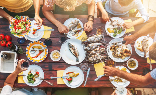 big miltigeneration family dinner in process. top view vertical image on table with food and hands - prepared fish seafood barbecue grilled imagens e fotografias de stock