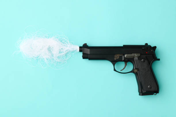 istock Black pistol with smoke on light blue background 1126287562