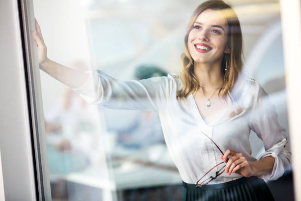 istock Young female standing next to window and smiling 1126290714