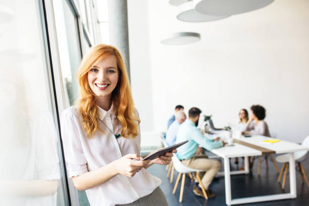 istock Young redhead businesswoman using tablet in the office 1126297323
