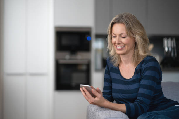 istock Happy woman at home using app on her cell phone 1126300336
