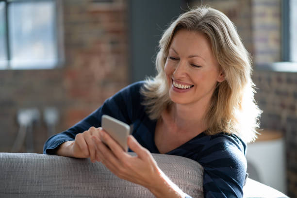 istock Beautiful woman at home using app on her cell phone 1126300341