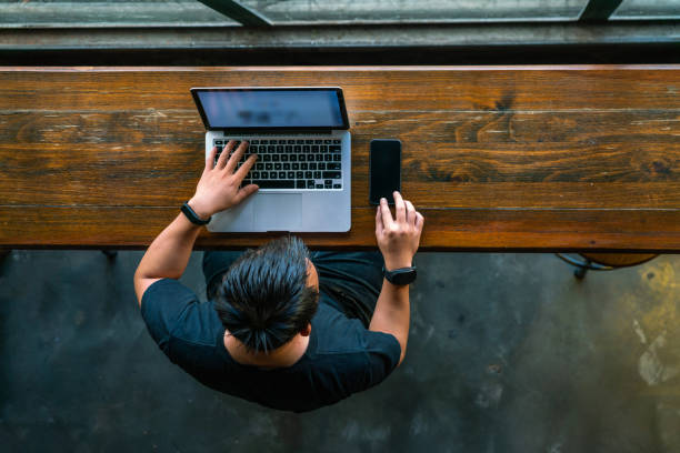 istock High angle view of Asian man working on smartphone and laptop 1126307928