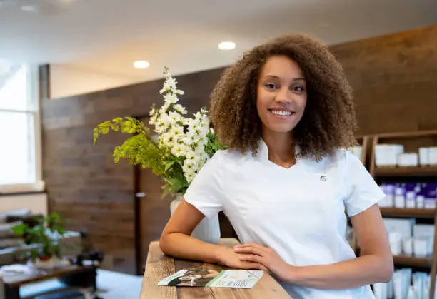 Portrait of a business owner working at a spa and looking at the camera smiling - beauty concepts. **DESIGN ON BROCHURE WAS MADE FROM SCRATCH BY US**