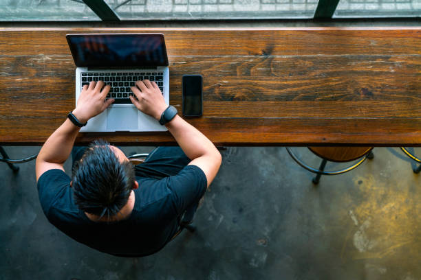 istock Young Asian businessman using laptop on wooden table 1126314358