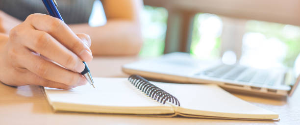 istock Woman hand is writing on notepad with pen in office. 1126331485