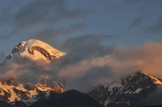 Photo of Snow-capped mountains Kazbek at dawn and the valley below where there is a church siete Trinity. Georgia.