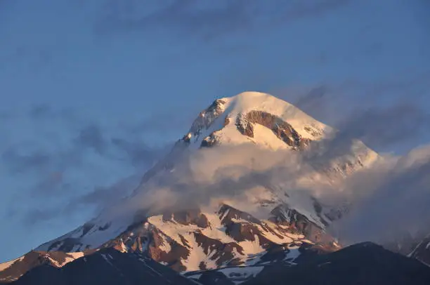 Photo of Snow-capped mountains Kazbek at dawn and the valley below where there is a church siete Trinity. Georgia.