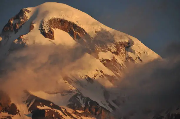 Photo of Snow-capped mountains Kazbek at dawn and the valley below where there is a church siete Trinity. Georgia.