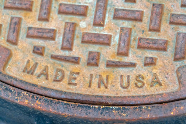 Round and rusty manhole cover made in USA. Close up view of a round and rusty manhole cover on a road in Utah Valley. The weathered manhole cover is made in the United States of America.