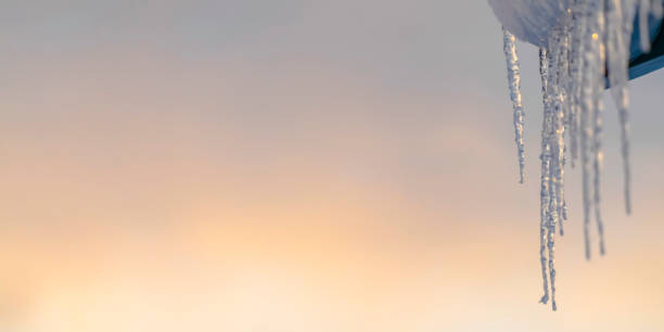 istock Sparkling icicles on a roof with sky background 1126339599