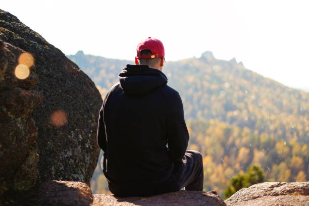 istock Young guy sitting on the mountain. Looking at the mountain scenery 1126343952