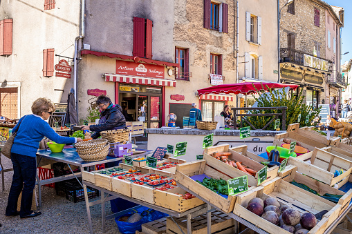 Sault, Provence, France - October 3, 2018: Tourist buying fresh vegetable and fruit at outdoor market in village of Provence.