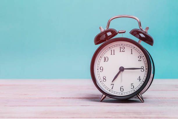 istock A Black Retro alarm clock on wooden board with green background 1126355363