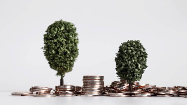 istock Two miniature trees on a pile of coins. 1126358792