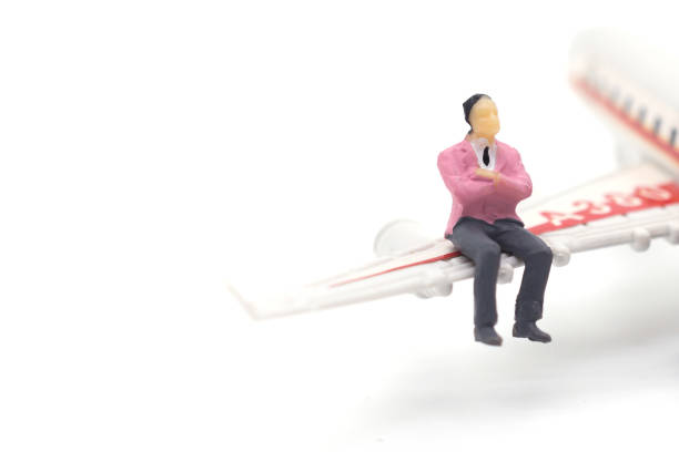 istock Miniature businessman sitting on airplane wing on white background 1126359730