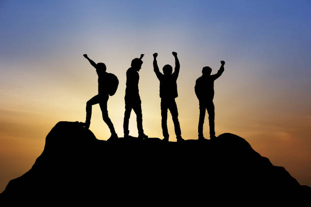 ピーク登山支援チームでの作業の成功ビジネス勝者の概念をトレッキング旅行、夕日を背景に人々 のグループ - climbing achievement leadership adventure ストックフォトと画像