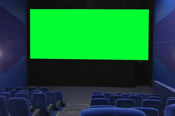 View of the empty cinema hall and a large green screen from the top rows. Cinema with rows of blue chairs