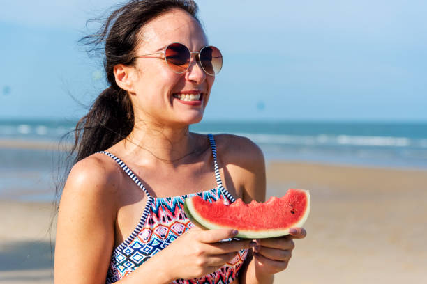 istock Young woman holding watermelon at the beach 1126364396