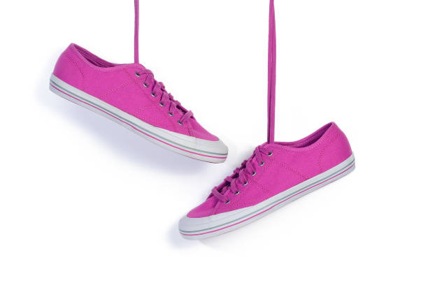 istock Fuchsia sneakers hang on laces isolated on a white 1126369882