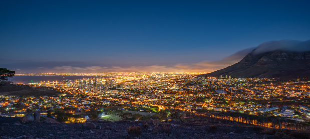 Beautiful illuminated Cape Town Cityscape Panorama at Twilight. Glowing City Lights of the ‚Mother City’ under the Table Mountain. Cape Town, Western Cape, South Africa, Africa. XXXL Panorama Shot.