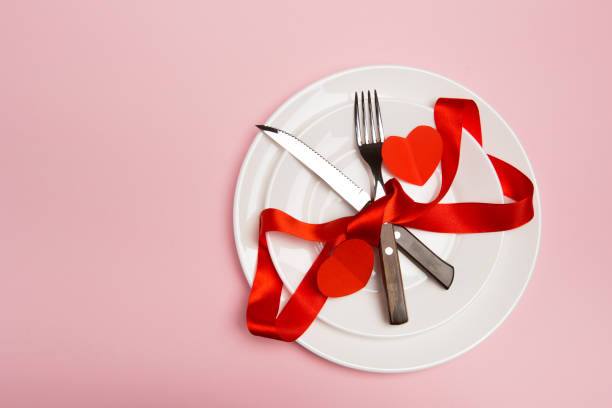 istock Festive table setting for Valentine's Day with fork, knife,  hearts on a red background. Top view. - Image 1126374256