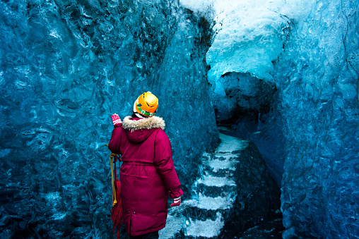 Woman exploring blue ice cave in Iceland back view