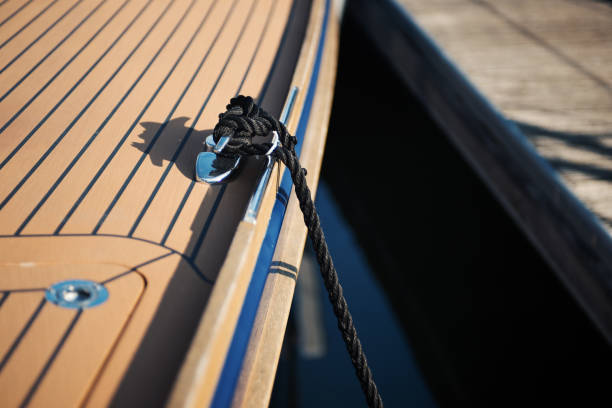 deck of wooden boat with coiled rope and docked boats in background.
