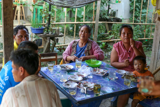 Luang Prabang, Laos - December 9, 2018: Local Lao (laotian) village people are celebrating, drinking beer and sitting by the table near Luang Prabang, former capital of Laos and now a UNESCO city. Luang Prabang, Laos - December 9, 2018: Local Lao (laotian) village people are celebrating, drinking beer and sitting by the table near Luang Prabang, former capital of Laos and now a UNESCO city. miao minority stock pictures, royalty-free photos & images