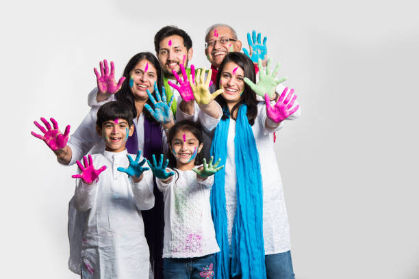family celebrating holi happy Indian/asian family celebrating Holi festival with colours. Multi generation people standing isolated over white background. selective focus beautiful traditional indian girl stock pictures, royalty-free photos & images