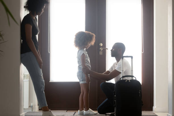 African dad talking to upset mixed race kid daughter leaving family with suitcase in hallway, black father saying goodbye to sad little girl, child of divorced parents and shared custody concept